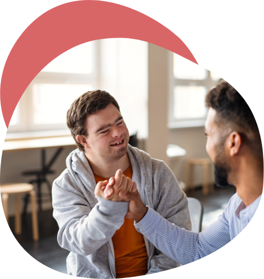 junger pflegebedürftiger Mann klatscht in die Hand seines Pflegers